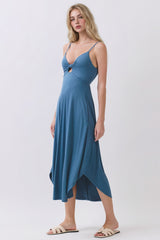 woman wearing a blue spaghetti strap midi dress with a front knot detail and an asymmetrical hemline