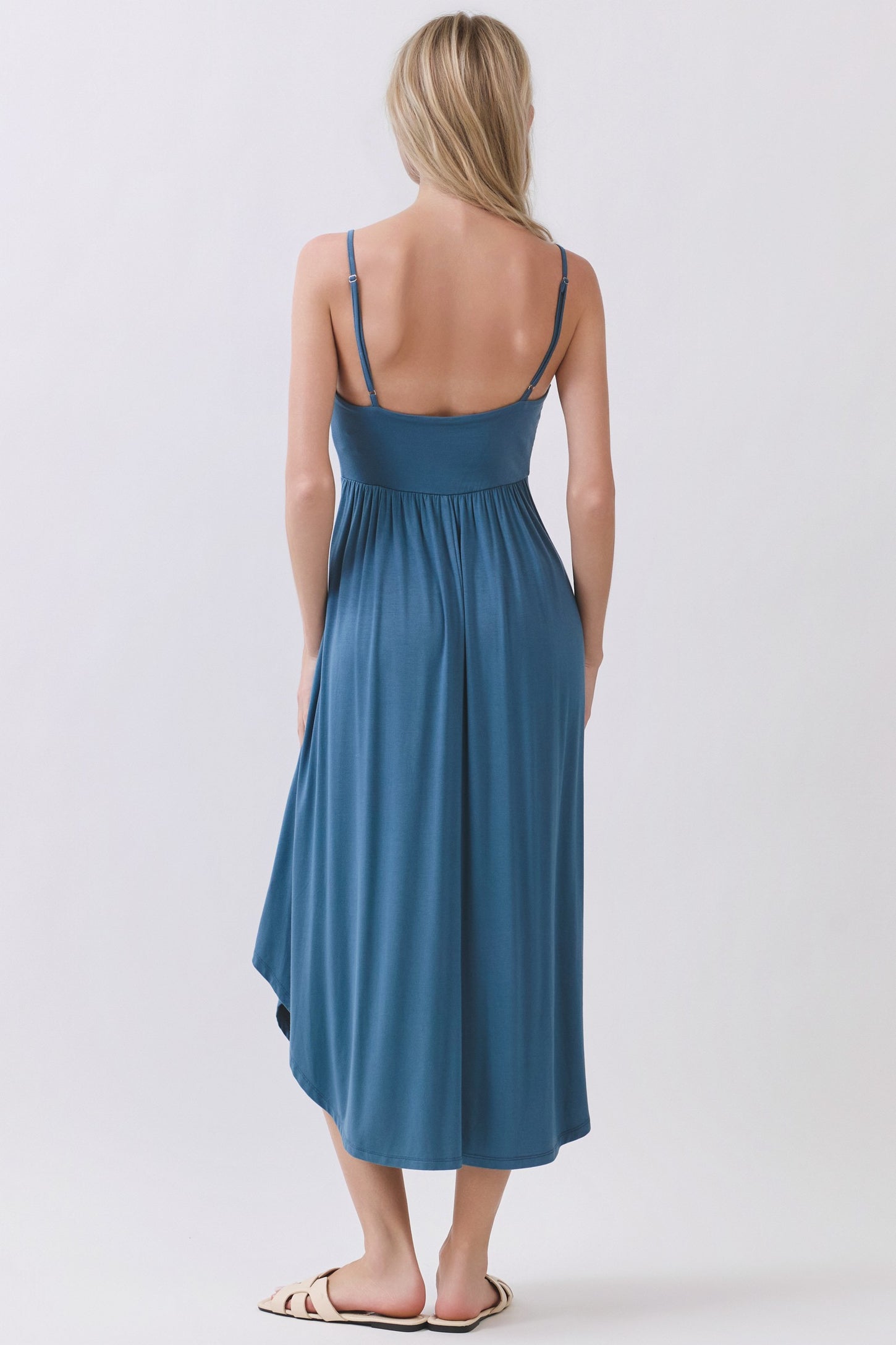 woman wearing a blue midi dress with adjustable straps and a flowy hem, shown from the back