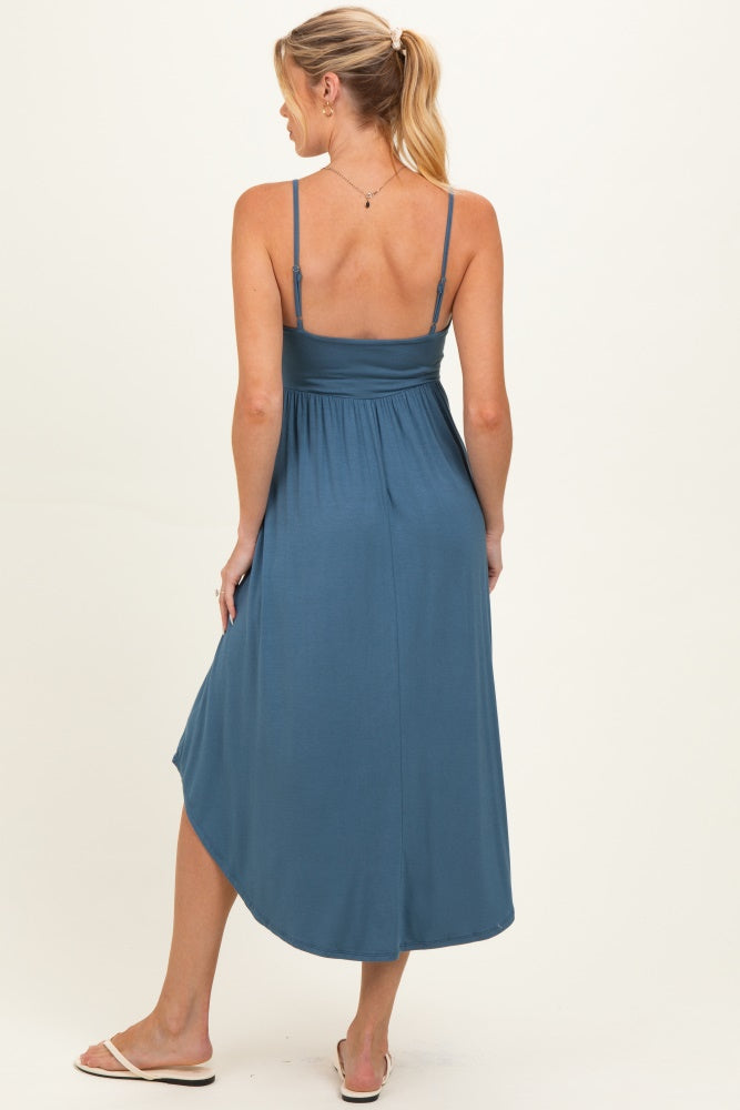 woman wearing a teal maternity maxi dress with adjustable straps and a flowy back design
