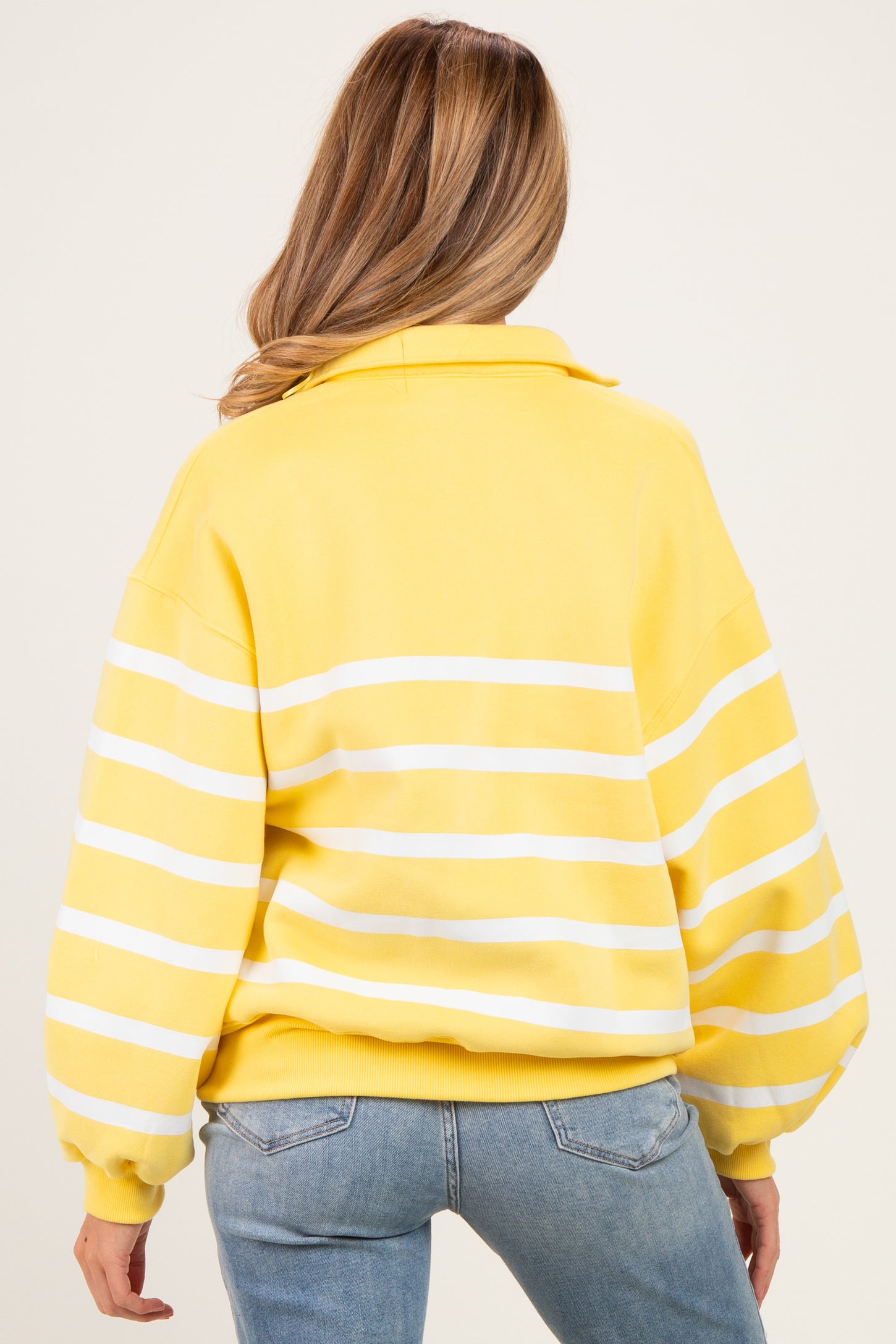 woman wearing a yellow and white striped oversized maternity sweatshirt, showing the back view