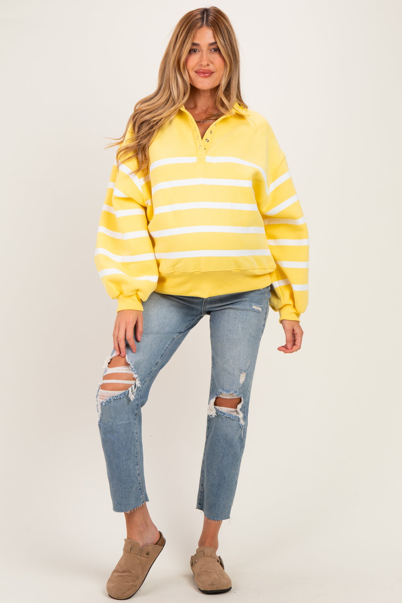 woman wearing a yellow striped maternity pullover sweatshirt and distressed blue jeans with a relaxed fit