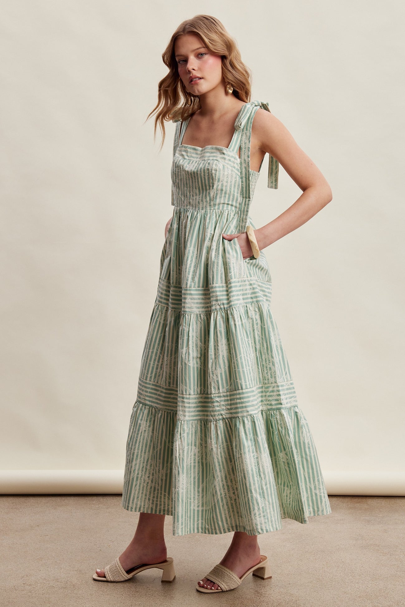 woman wearing a green and white striped maxi dress with tie straps and pockets