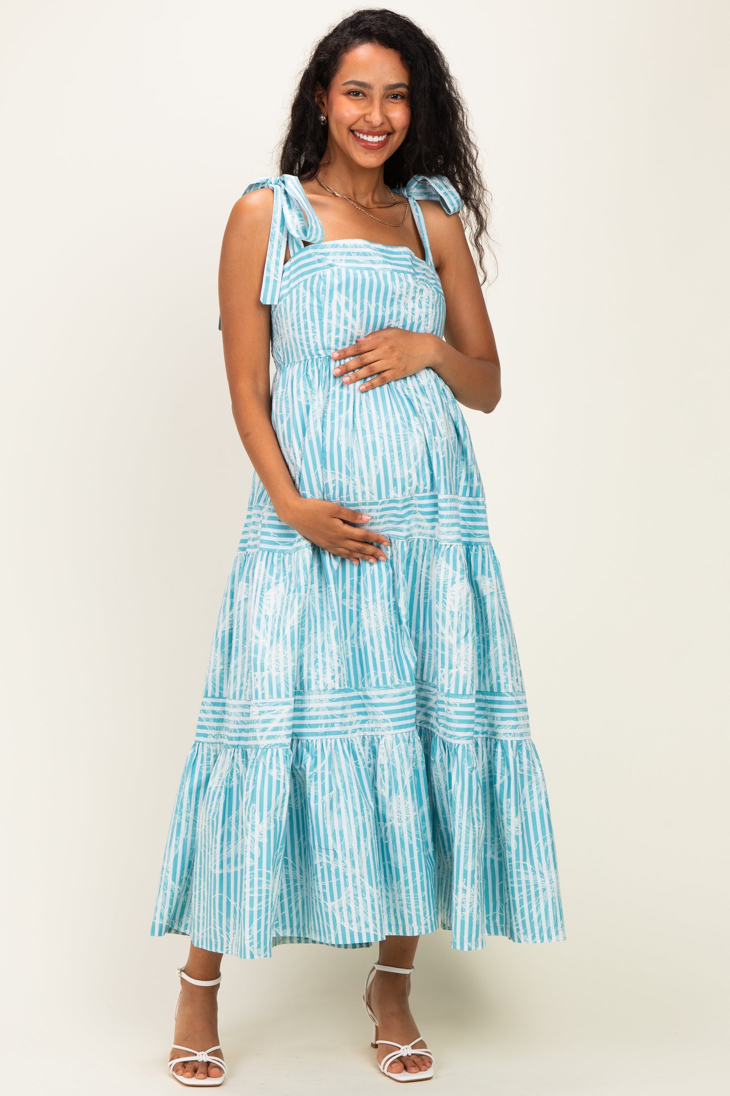 woman wearing a blue and white striped maternity dress with tie straps and a baby bump
