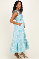 woman wearing a light blue striped maternity maxi dress with pockets and a visible baby bump