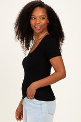 woman wearing a fitted black ribbed short sleeve top with a scalloped neckline and paired with light blue jeans
