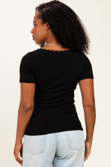 woman wearing a black ribbed short sleeve top with scalloped neckline, viewed from the back