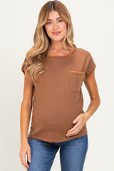 woman wearing a brown maternity top with orange trim and a front pocket, showing her baby bump while smiling