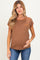 woman wearing a brown maternity top with orange trim and a front pocket, showing her baby bump while smiling
