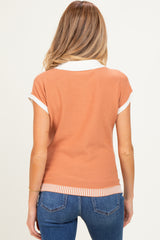 woman wearing a short sleeve rust-colored maternity polo with white collar and ribbed hem