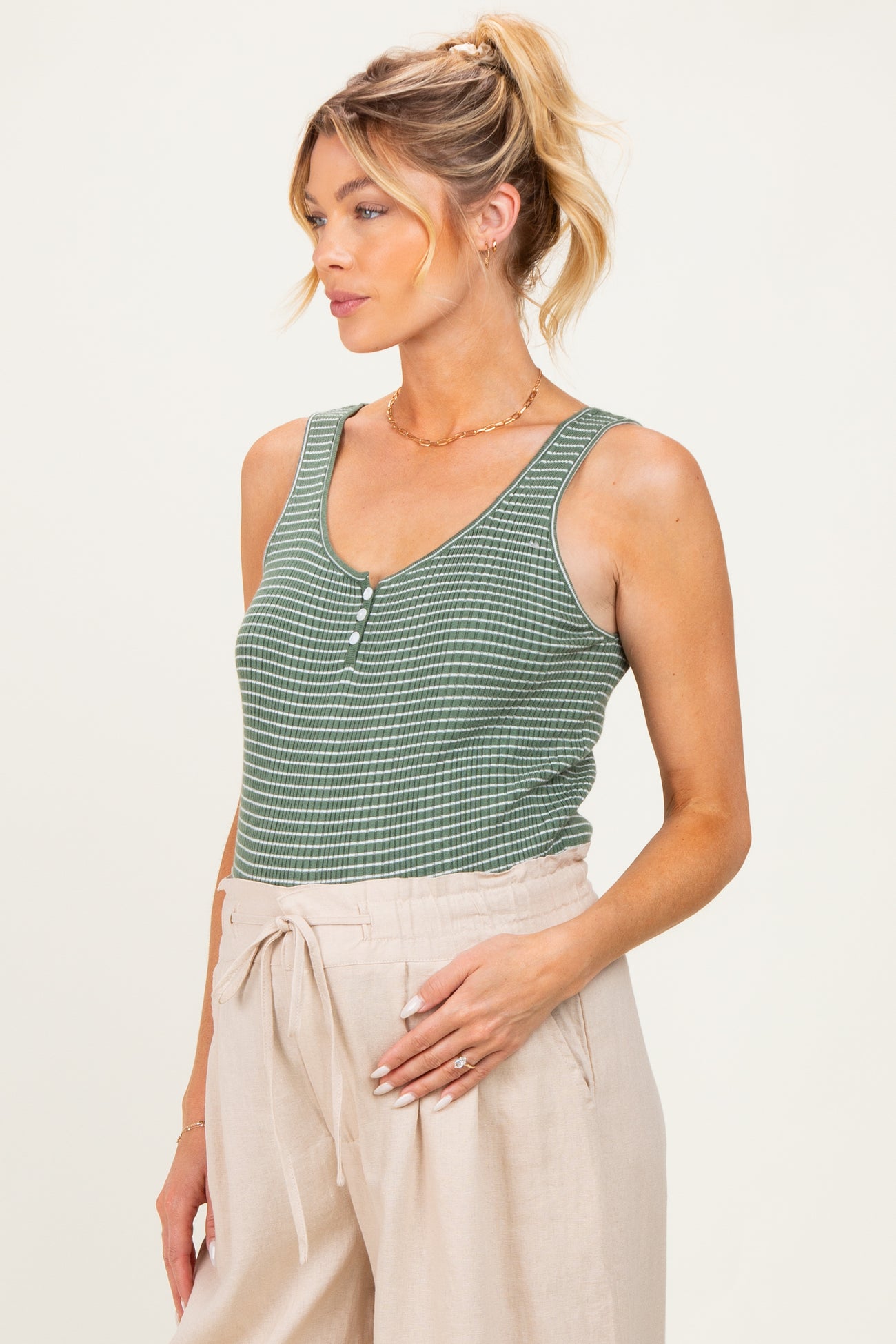 woman wearing a green and white striped maternity tank top and holding her baby bump