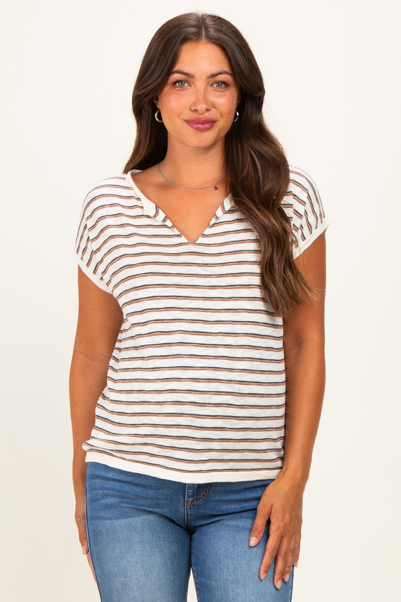 woman wearing a striped maternity top with a v-neck and short sleeves paired with blue jeans