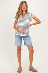 woman wearing a striped maternity top and blue denim shorts, holding her baby bump