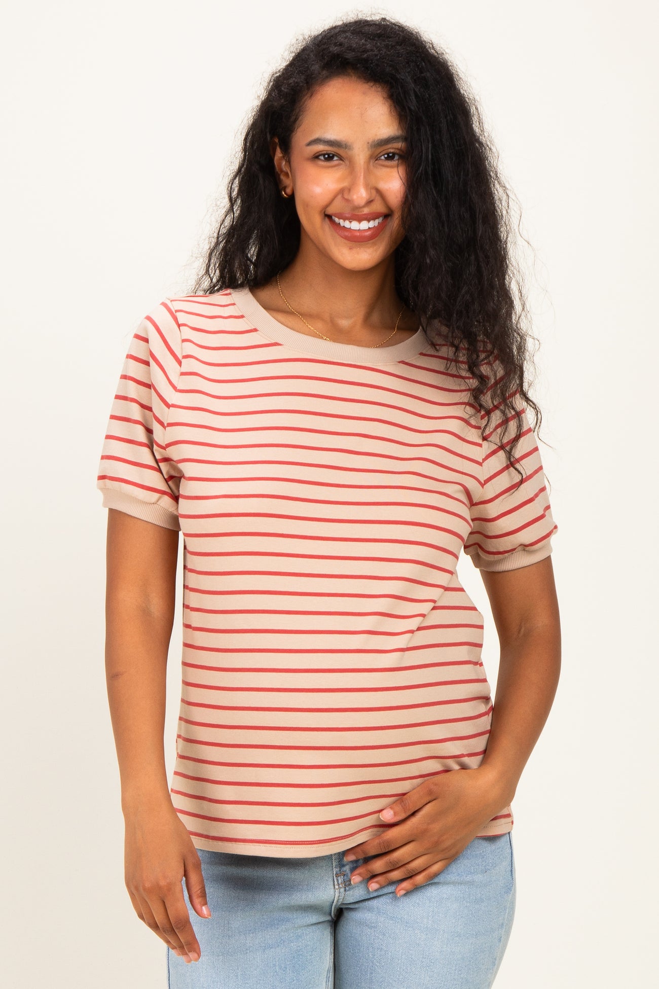 woman wearing a beige striped maternity top with short sleeves and holding her baby bump