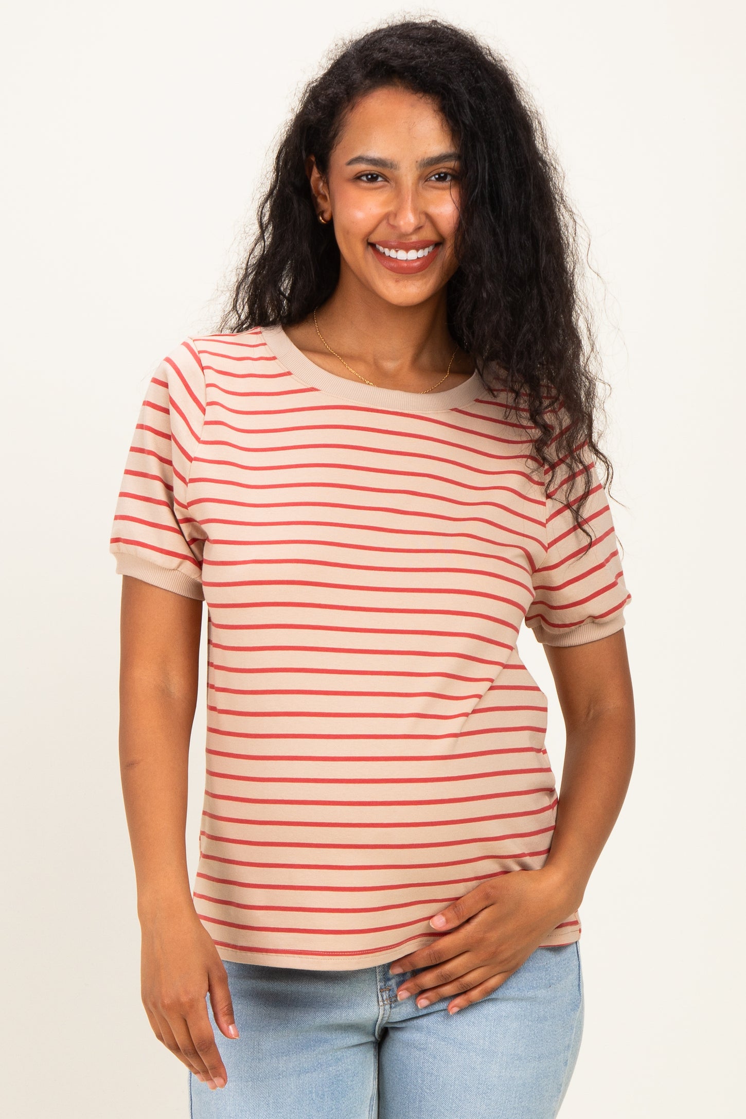 woman wearing a beige striped maternity top with short sleeves and holding her baby bump