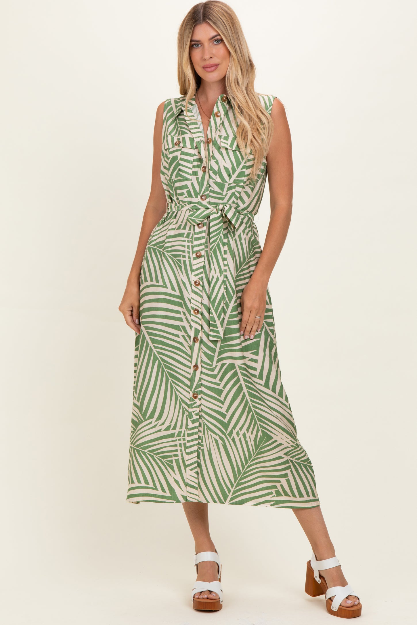 woman wearing a green and white striped sleeveless button-down dress with a tied waist and a flowy midi length