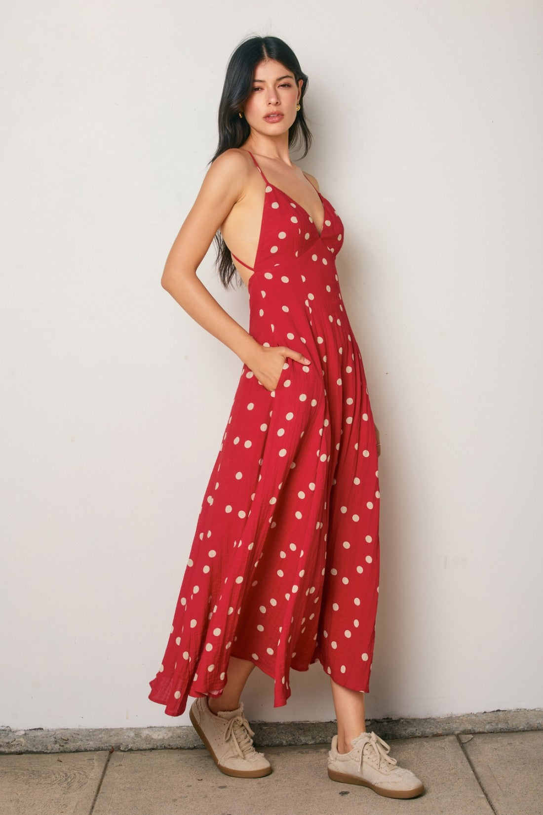 woman wearing a red polka dot maxi dress with a deep v-neck and pockets, styled with beige lace-up shoes
