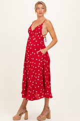 woman wearing a red polka dot maternity dress with a tied back and pockets, showcasing her baby bump