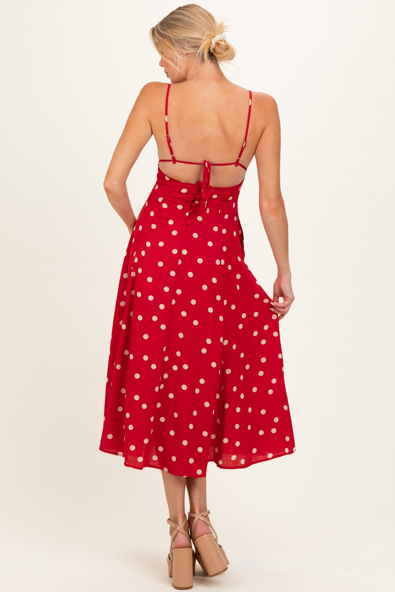 woman wearing a red polka dot maternity dress with a tie-back detail and flowy skirt