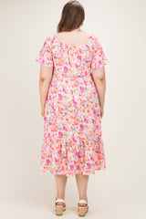 woman wearing a floral maternity plus dress with short sleeves and a tiered hem, shown from the back