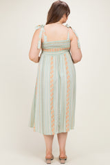 woman wearing a green and orange striped maternity dress with smocked bodice and tie straps, showing a baby bump from the back