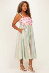 woman wearing a floral and striped plus-size midi dress with pockets and adjustable straps