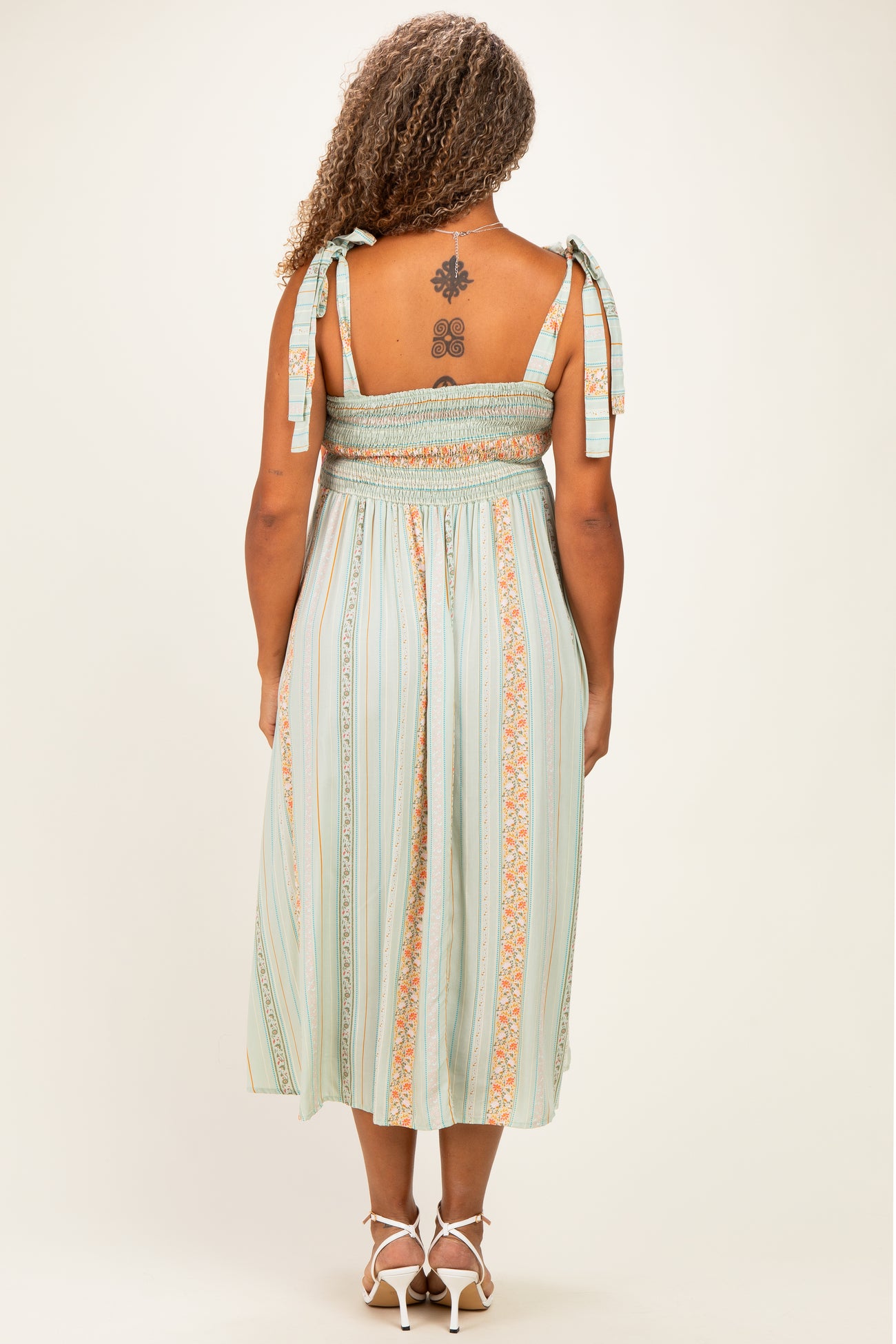 woman wearing a light green plus size midi dress with straps and smocked back detailing, seen from the back