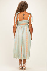 woman wearing a light green plus size midi dress with straps and smocked back detailing, seen from the back
