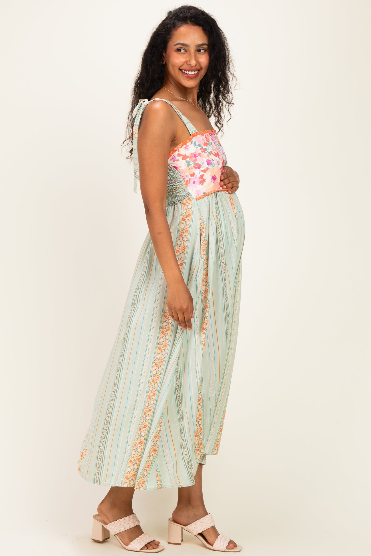 woman wearing a floral print maternity maxi dress with a smocked bodice and straps, showing her baby bump