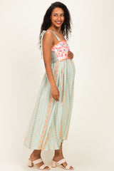 woman wearing a floral print maternity maxi dress with a smocked bodice and straps, showing her baby bump