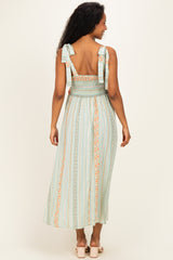 woman wearing a mint green maternity dress with smocked bodice and ribbon straps, showing a flowing skirt from the back