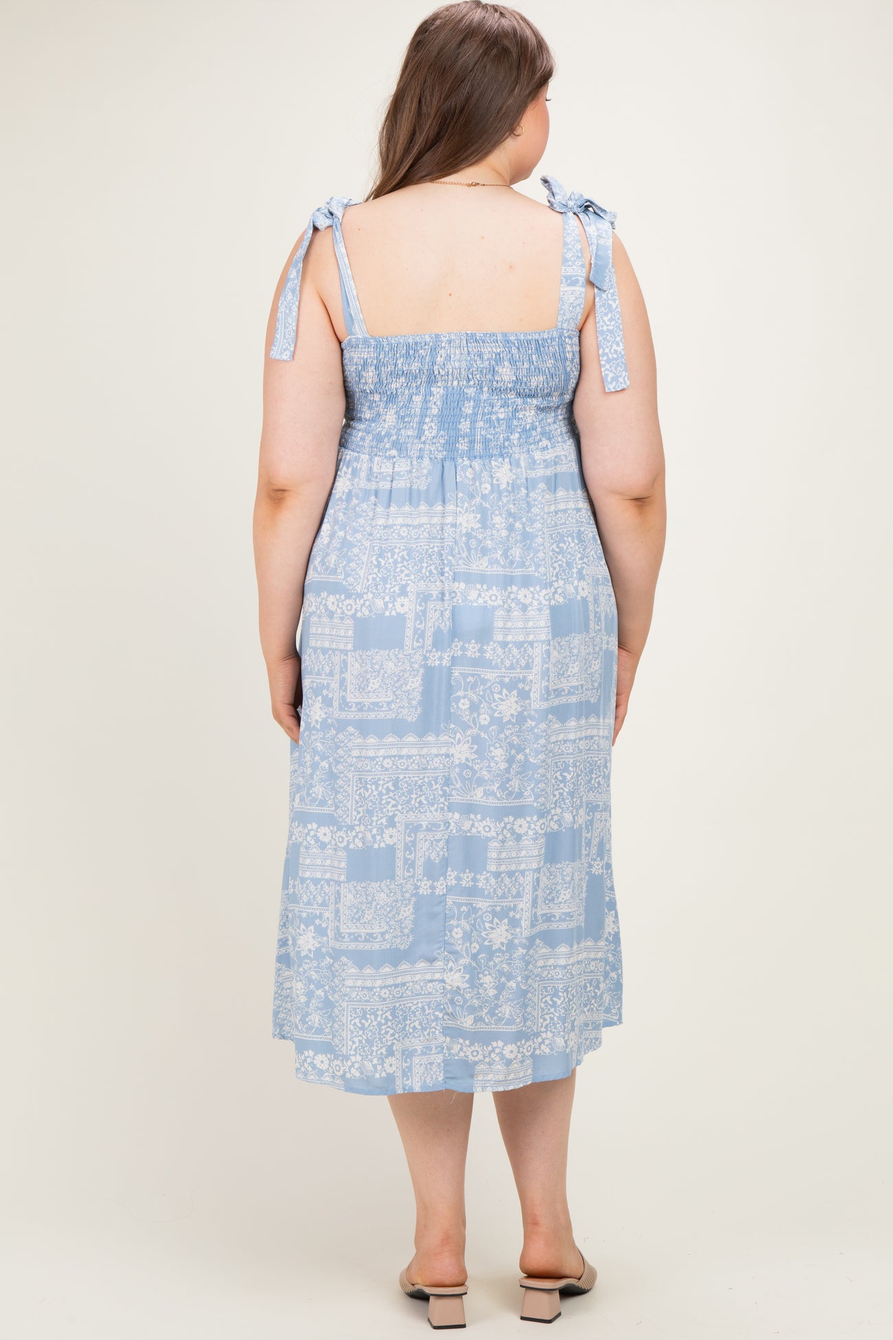 woman wearing a light blue floral print maternity plus sundress with smocked back and tie shoulder straps
