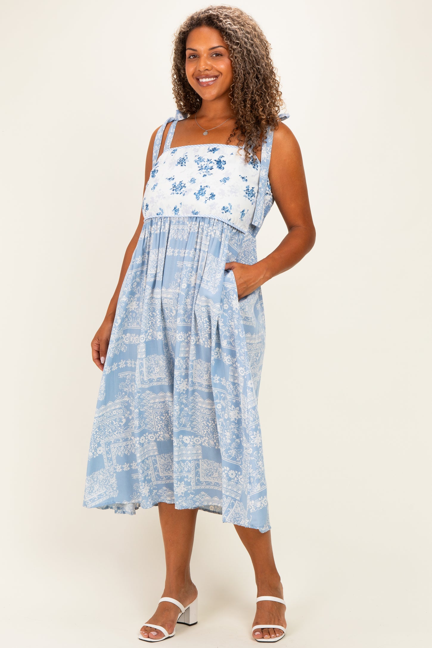 woman wearing a blue plus size sundress with floral print, shoulder straps, and pockets