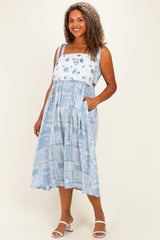 woman wearing a blue plus size sundress with floral print, shoulder straps, and pockets
