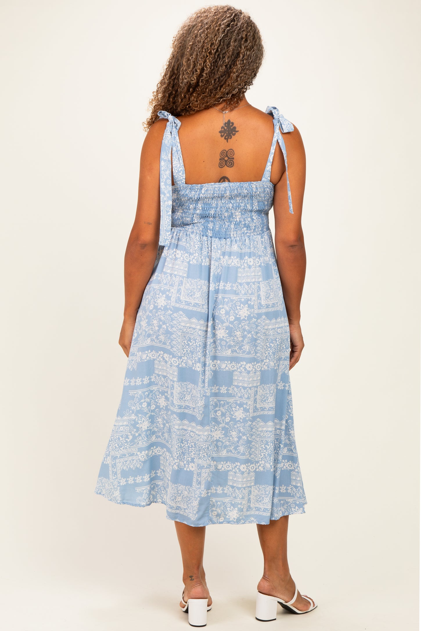 woman wearing a blue floral print plus size sundress with tie shoulder straps and smocked back