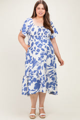 woman wearing a white and blue floral print maternity dress with short sleeves and pockets in a flowing style