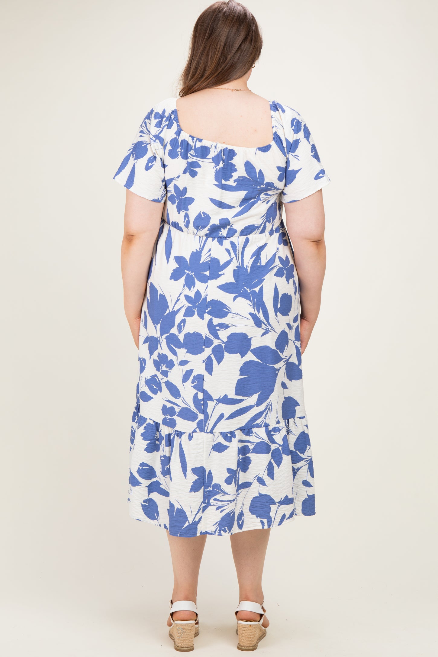 woman wearing a maternity plus floral print midi dress in blue and white with short sleeves and tiered skirt