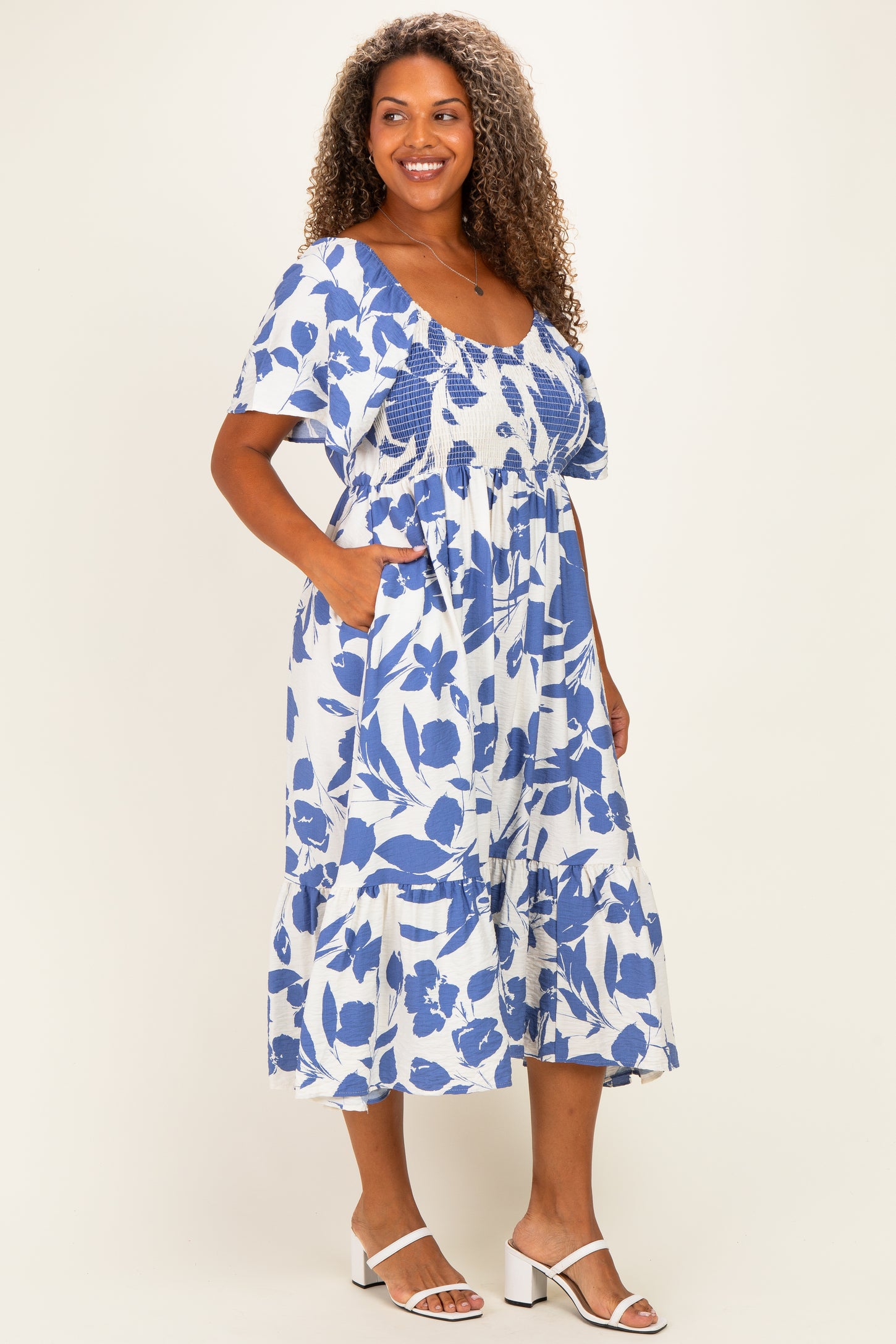 woman wearing a blue and white floral plus size midi dress with short sleeves and pockets