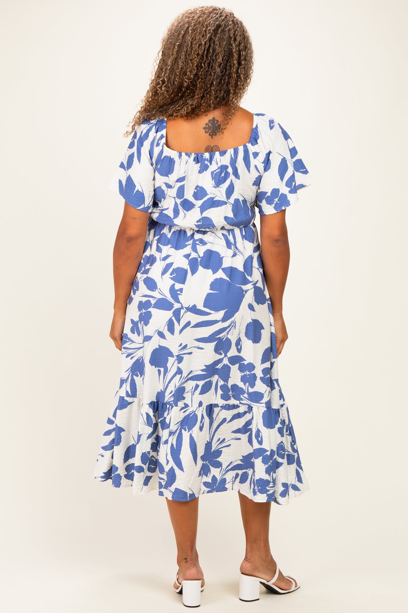 woman wearing a blue and white floral plus size midi dress with short flutter sleeves and a tiered skirt