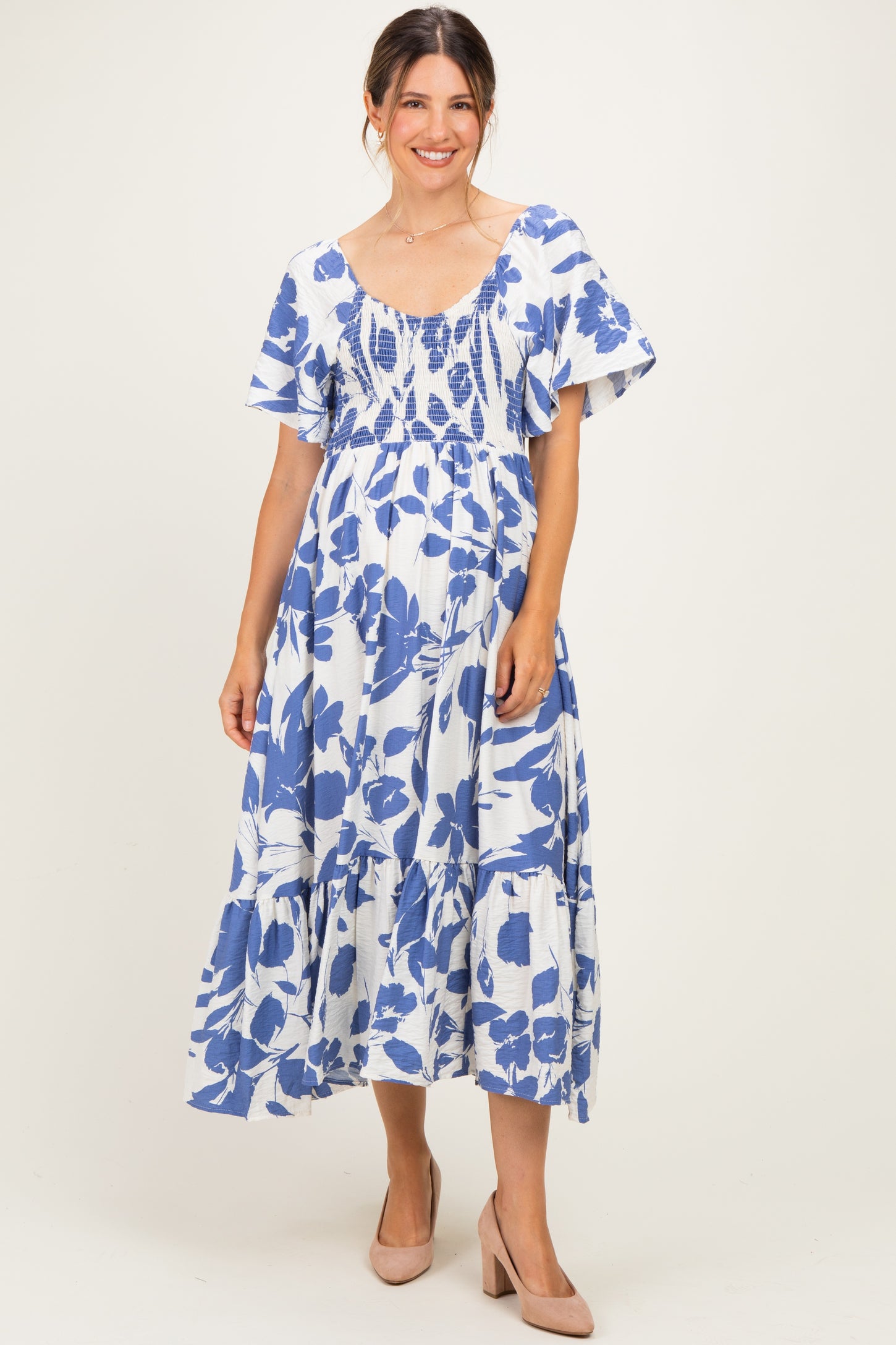 woman wearing a blue and white floral maternity dress with a smocked bodice and short flutter sleeves