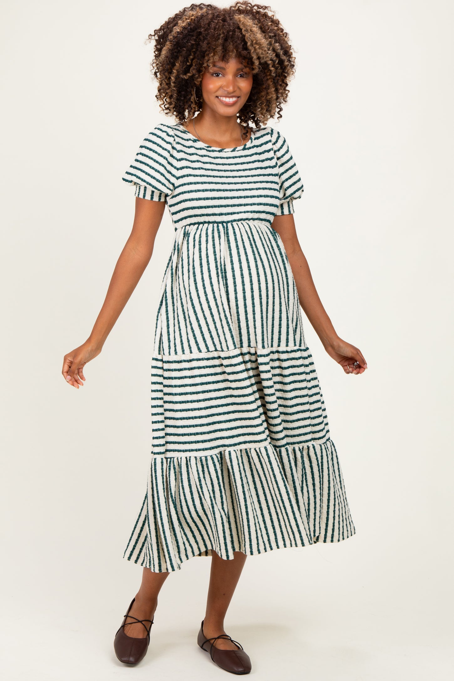 woman wearing a green and white striped maternity maxi dress with tiered layers and short sleeves, showing her baby bump