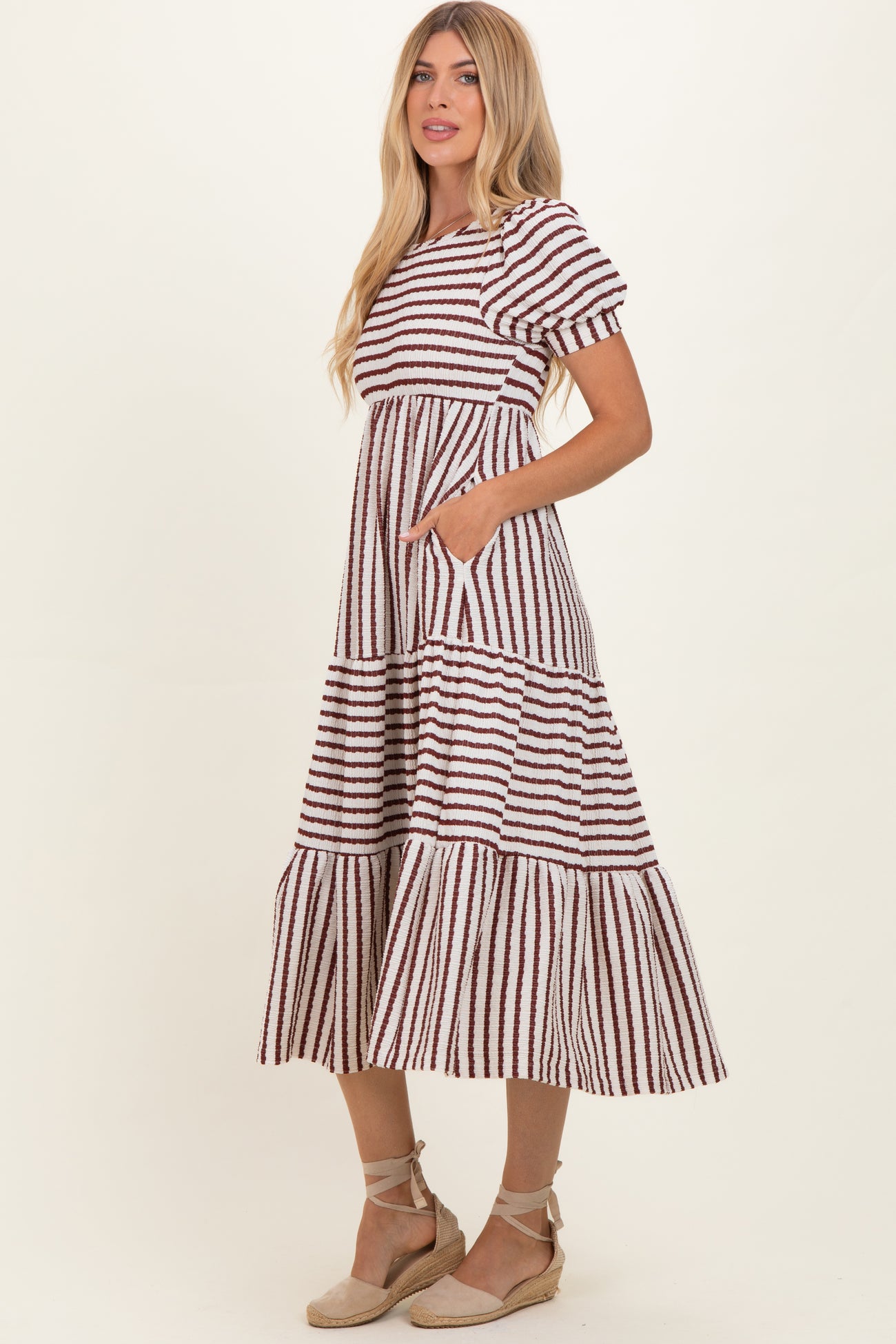 woman wearing a striped maxi dress with puff sleeves and pockets, featuring a tiered skirt and a relaxed fit