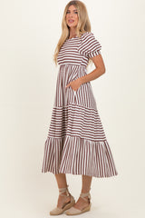 woman wearing a striped maxi dress with puff sleeves and pockets, featuring a tiered skirt and a relaxed fit