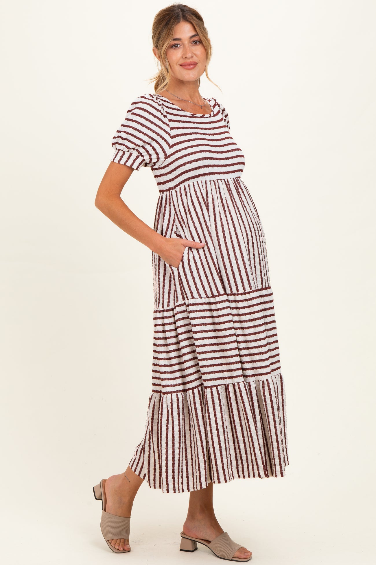 woman wearing a striped maternity maxi dress with short sleeves and pockets, showcasing her baby bump