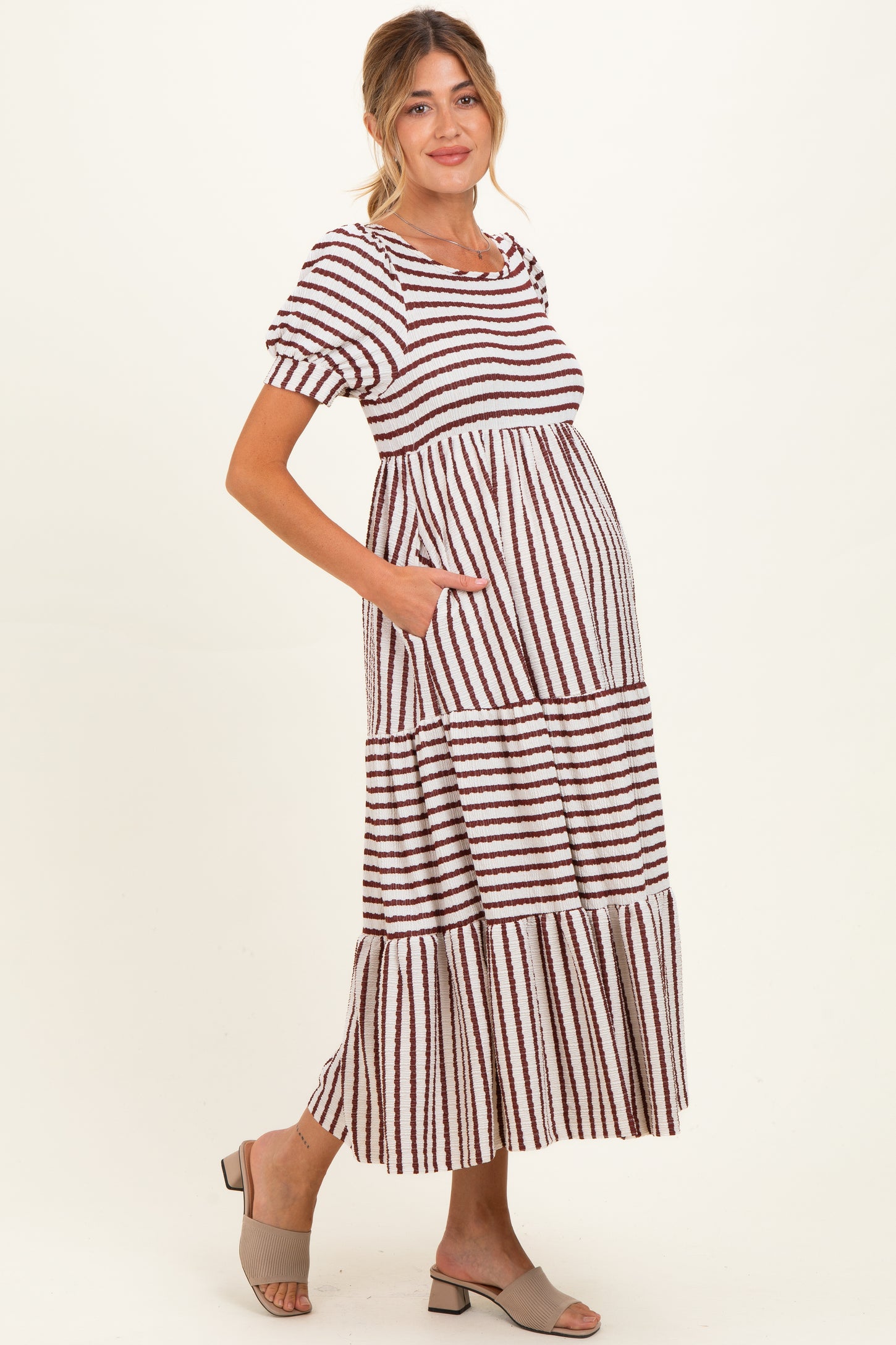 woman wearing a striped maternity maxi dress with short sleeves and pockets, showcasing her baby bump