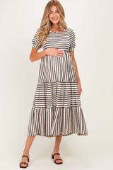 woman wearing a black and white striped maternity maxi dress with tiered ruffles and holding her baby bump