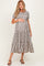 woman wearing a black and white striped maternity maxi dress with tiered ruffles and holding her baby bump