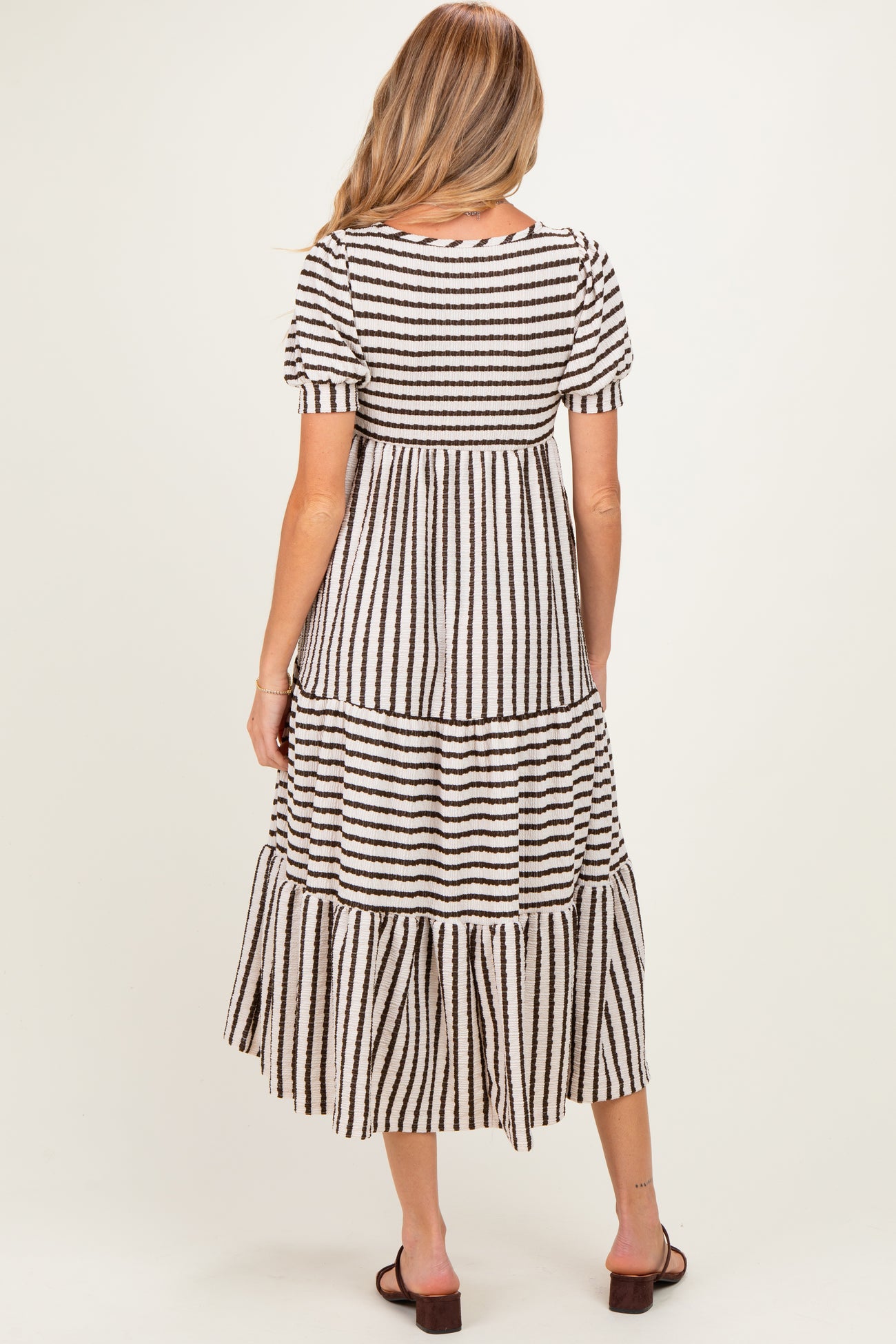 woman wearing a striped maternity dress with short sleeves and a tiered skirt, showing a relaxed fit