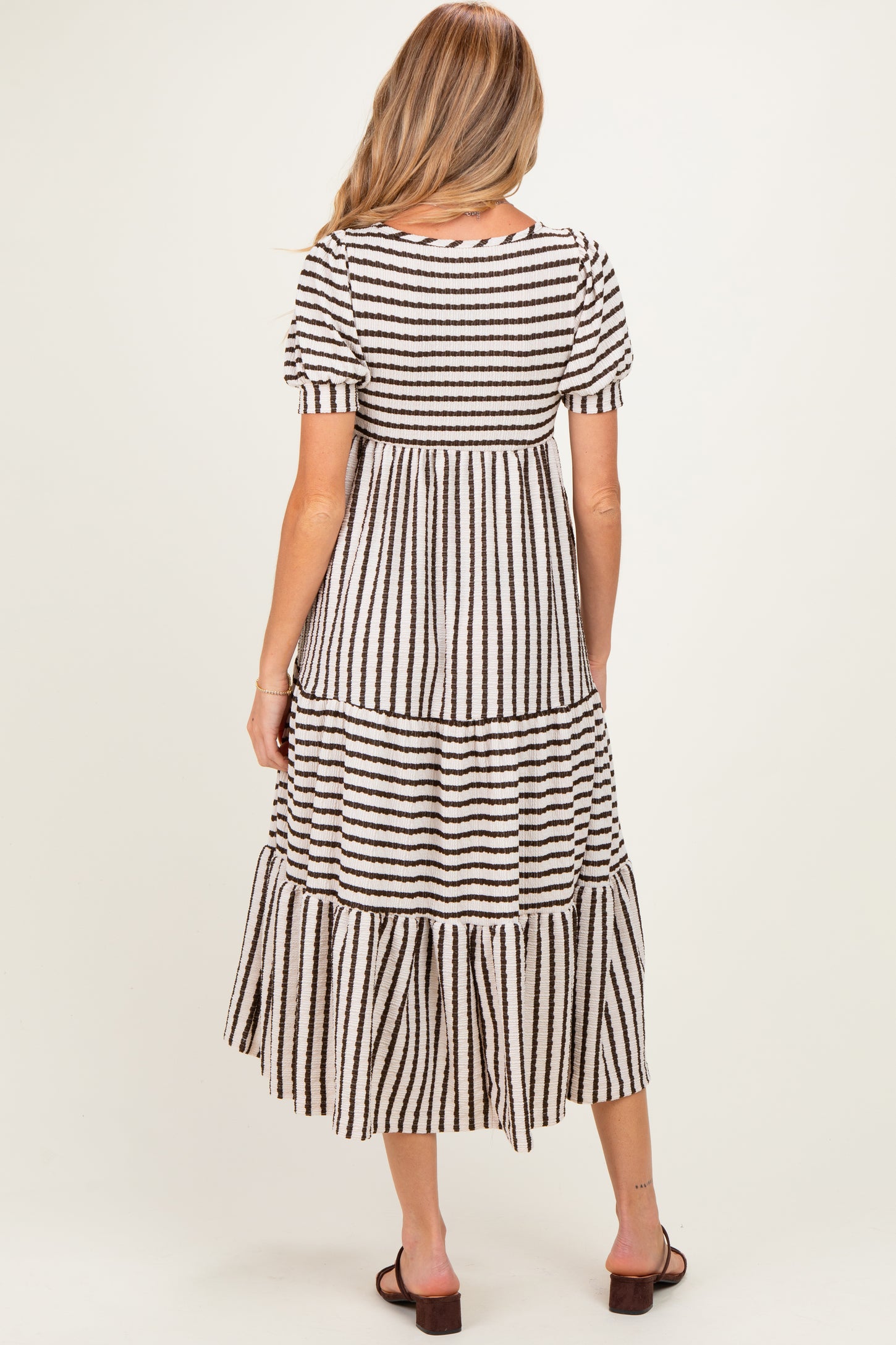 woman wearing a striped maternity dress with short sleeves and a tiered skirt, showing a relaxed fit