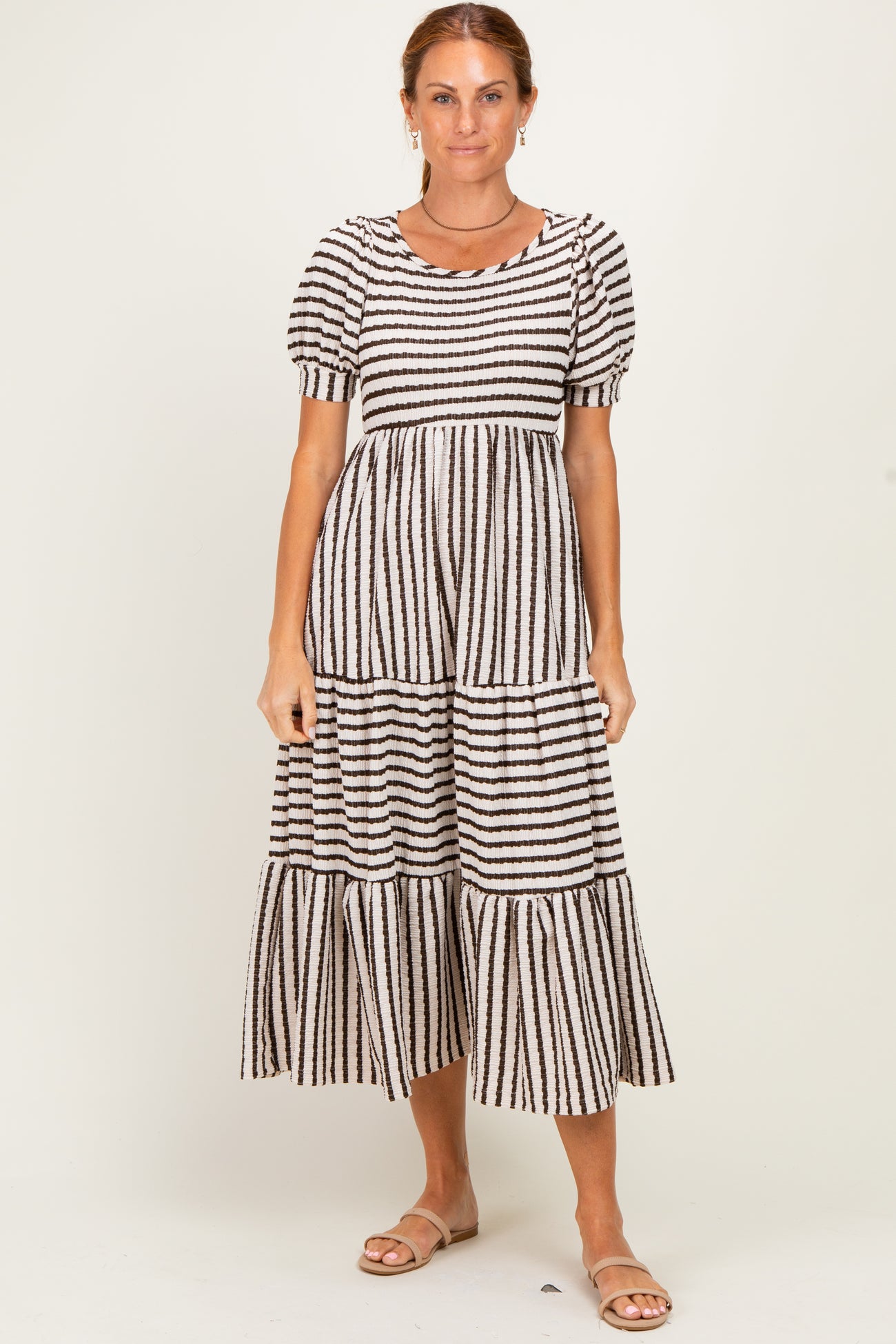 woman wearing a black and cream striped tiered midi dress with puff sleeves and a round neckline