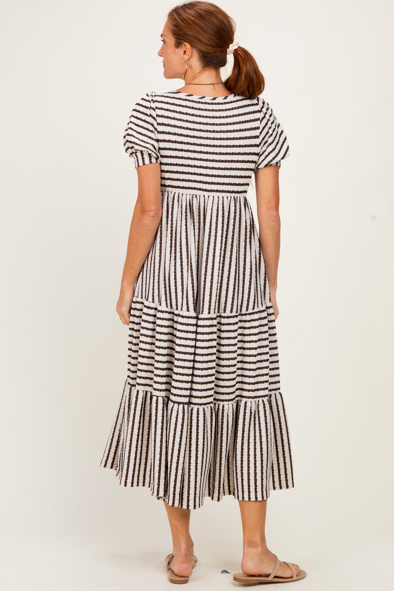 woman wearing a tiered striped maxi dress with puff sleeves and a relaxed fit, viewed from the back
